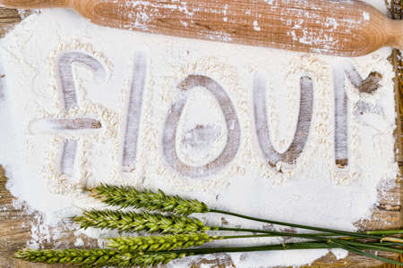 white wheat flour on which are squeezed out letters denoting the word flour, an old wooden tableの写真素材