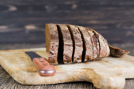black rye bread cut with a knife on a cutting Board, close-up of traditional foodの写真素材