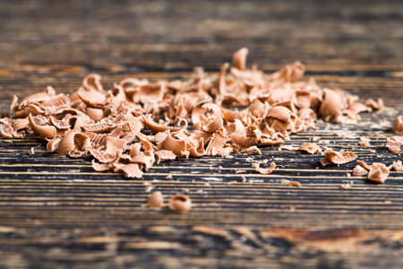 broken crumbs of delicious sweet milk chocolate during the preparation of desserts, details of sweets on the wooden tableの写真素材