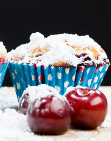 cherry muffins in white sugar topping on wooden table, fresh soft pastry productの写真素材