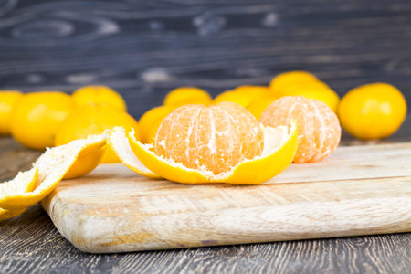 peeled orange juicy tangerine on a wooden table, close-up of ripe sour healthy citrus, winter fruits