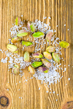ripe roasted pistachios with salt on a wooden surfaceの写真素材