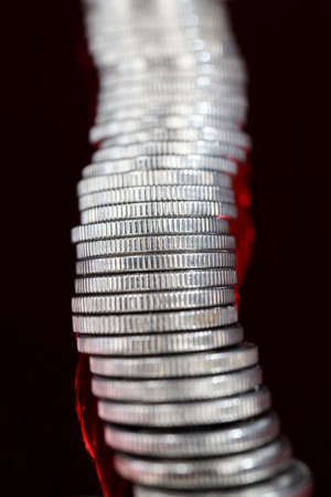 a large number of pile of beautiful old coins with ribbed side, lie together, close-up photo of real metal money illuminated by colored lightの写真素材