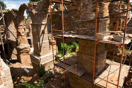 old brickwork of different bricks and ruined and dilapidated arches, is part of the old castle, the restoration of the fortress, scaffolding installedの写真素材
