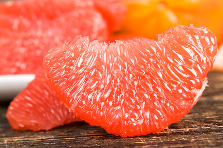 peeled delicious red grapefruit ready for food, pieces lying on the table, closeup