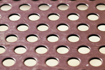 metal surface with round holes for ventilation or cheaper construction, close up