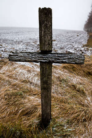 old wooden Catholic cross against blue sky and white clouds in Sunny weather, close-up of religious symbols in winterの写真素材