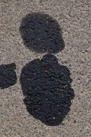 oil black spots on the asphalt of the road from cars in need of repair, environmental pollution from human action, transport breakdownsの写真素材