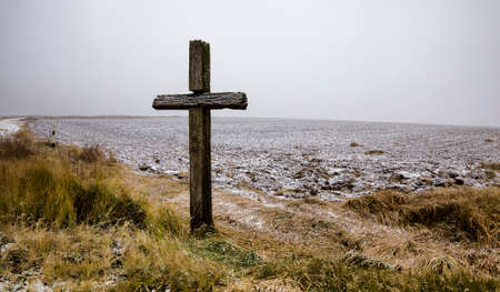 old wooden Christian cross against blue sky and white clouds in Sunny weather, close-up of religious symbols in winterの写真素材
