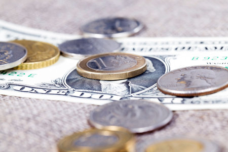 American paper dollar and European coin lie together, close-up of metal banknotes together in paper...