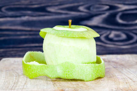 peeled green Apple on a wooden cutting Board, close-up of food of natural productionの写真素材