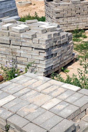 Packed large and long new concrete blocks for curbs and pavers lie on the ground at the construction...