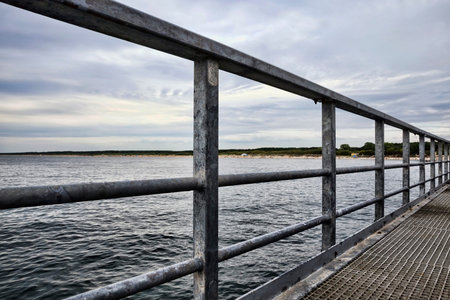 long pier in the sea with waves on the water during sunset or sunrise, seascape on the Baltic sea