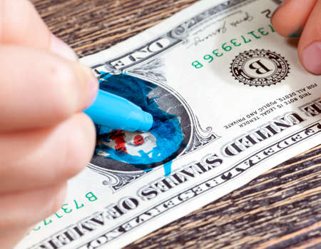painted with blue markers and completely destroyed one American dollar, a close-up of American money, the concept of a crisis where dollars are just paperの写真素材