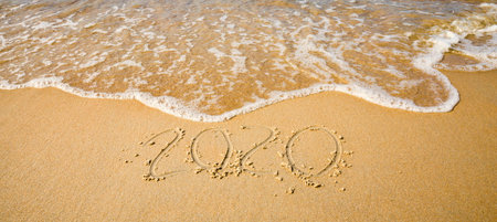 sea waves erasing the inscription of the year 2020 on the sea sand, close-up on vacation on...