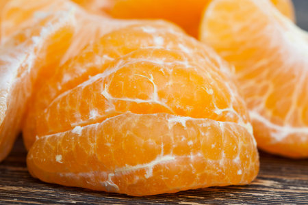 peeled delicious tangerine ready for food, pieces lying on the table, close-up