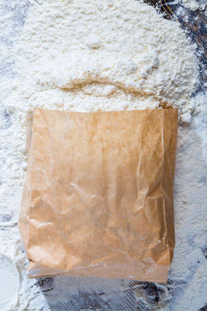 a paper bag of flour on the table, some white wheat flour spilled out of the bagの写真素材