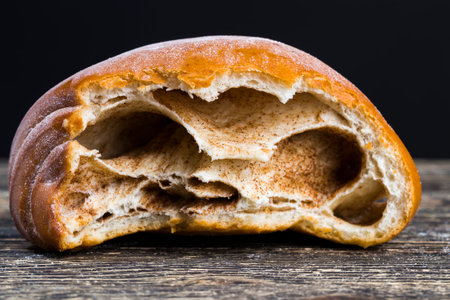 bitten fresh wheat soft bun with ground cinnamon filling, closeup