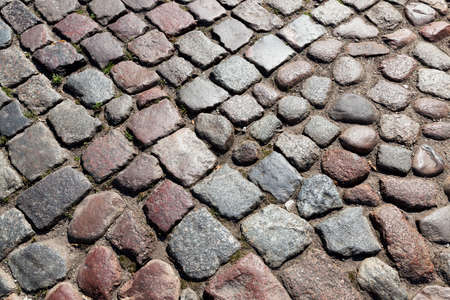 multi-colored road made of stones and cobblestones for traffic and people, stylized in the old days, close upの写真素材