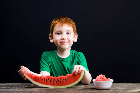 a small boy bites watermelonの写真素材