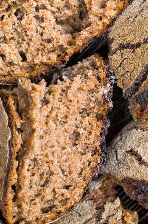 black homemade rye flour bread, close-up of food on kitchen cutting Board, cooking lunch of crispy bread broken into piecesの写真素材