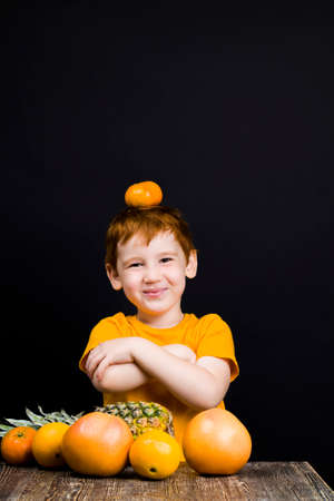 a beautiful red-haired boy with citrus fruitsの写真素材