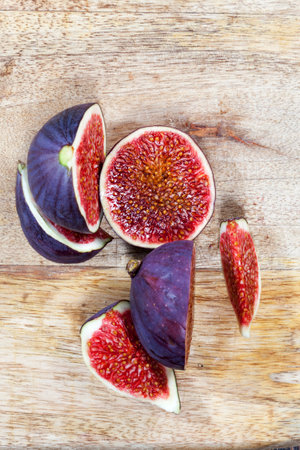 sliced fruit of ripe figs on a wooden kitchen board, close-up of figs for cooking, red delicious fig pulpの写真素材