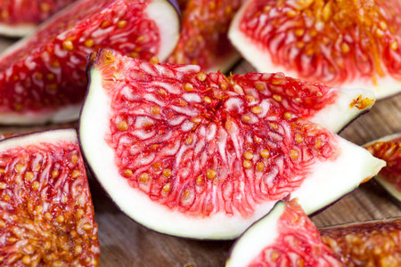 sliced fruit of ripe figs on a wooden kitchen board, closeup of figs for cooking, red delicious fig...