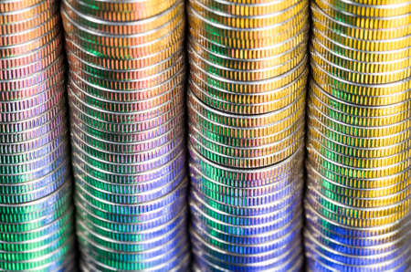 group of coins close-up, coins have damage and defects due to use, cash coins of silver color are illuminated with colored light and have a multi-colored tone and shadesの写真素材