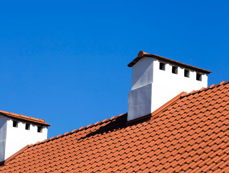 painted chimneys on the roof of an orange color, made of tiles, closeup of the roof of the building