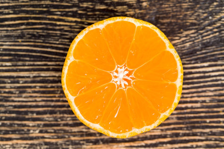 Sliced across the oranges lying on the black wooden floor, closeup of citrus fruits