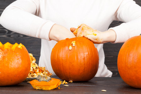 Cut pumpkin from which they prepare either food or Halloween preparation, a woman in a white jacketの写真素材