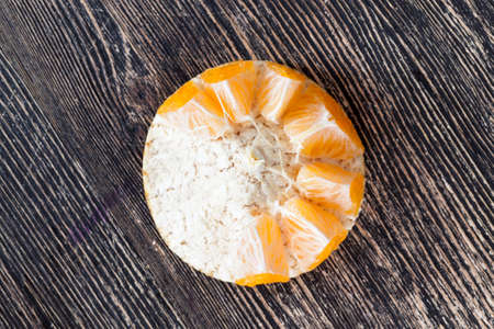 Sliced tangerine lying on a wooden surface, closeup of citrus fruitsの写真素材