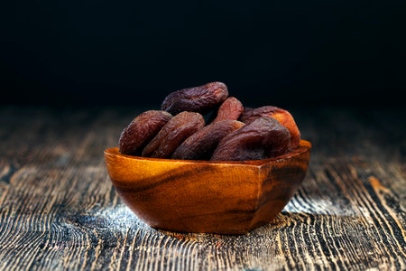 dried apricots made from natural apricots, dried apricots of dark color, natural drying without the use of acceleration and chemical elements, dry fruits on a wooden tableの写真素材