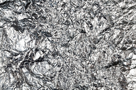 thin and crumpled shiny aluminum foil, used in cooking for cooking, closeup
