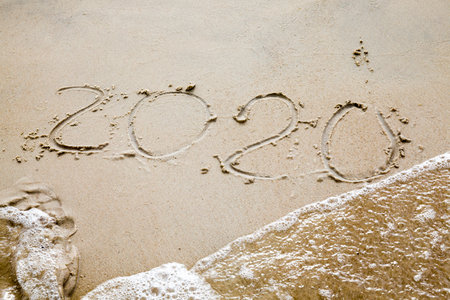 photo of sand on the beach, the numbers 2020 are drawn on the sand, the year 2020, which is washed away by waves from the sea, closeupの写真素材