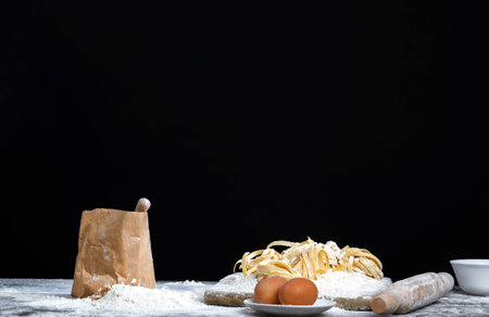 white wheat flour in a paper bag with wooden spoon, collected parts ingredients for cooking pasta...