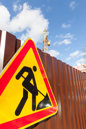 road sign for repairs installed on a metal fence to protect the construction site, road sign on the...