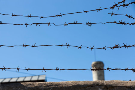 old barbed wire against the blue sky, fencing private territories and private property with passive...