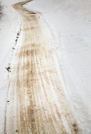 dirty snow on the road after a lot of cars have passed along the road, the winter season with snowの写真素材