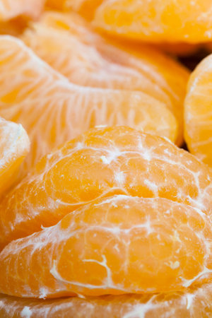 cleaned from the peel tasty oranges are ready for eating, the pieces lying on the table, close-up