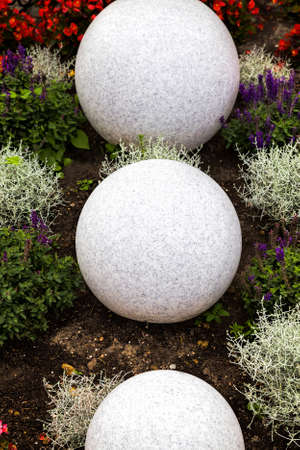 large stone balls on flower beds for decoration, closeup in a Park for recreationの写真素材