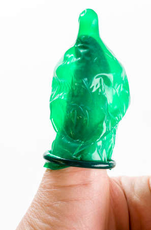 green latex condom on the finger, a means to prevent pregnancy and STDs and infection, close-up and small depth of fieldの写真素材