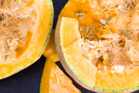large-sized pumpkin cut with large seeds and, while preparing a dish, healthy vegetables, cooking...