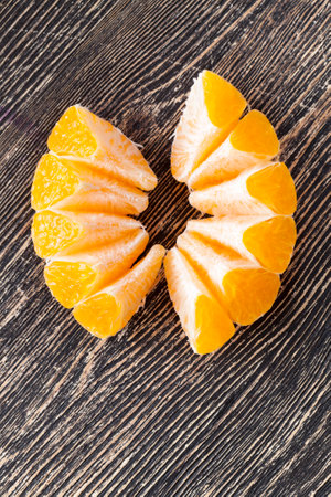 A ripe orange or mandarin cut into several pieces, close-up, the structure of an orange fruit is visibleの写真素材