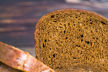 Freshly baked black rye bread, fragrant warm bread, was cut into pieces at home or in industrial...
