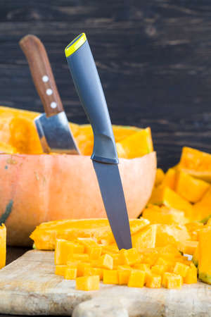 sliced and diced orange pumpkin on the kitchen table, close-up of raw vegetables before cookingの写真素材