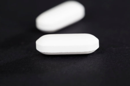 White pill lying on a black background, Focus 1 tablet in the foreground