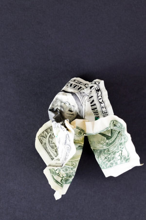 cash American dollars wrinkled and lying on a black sheet of paper, close-up