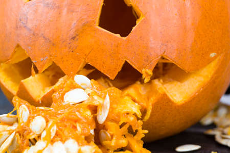 single orange pumpkin lying on a black wooden table cut for a jack lamp for halloween, close-up in the kitchenの写真素材